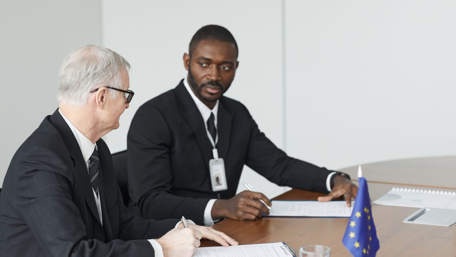 Choice of Law and Forum Clauses as International Business Dispute Strategy Two executives review a contract at a conference table beside an EU flag, illustrating choice of Law and Forum Clauses as International Business Dispute Strategy